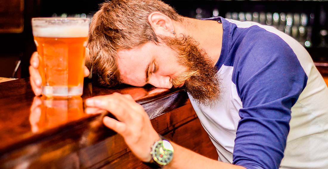un homme avec une chope de bière dort au bar